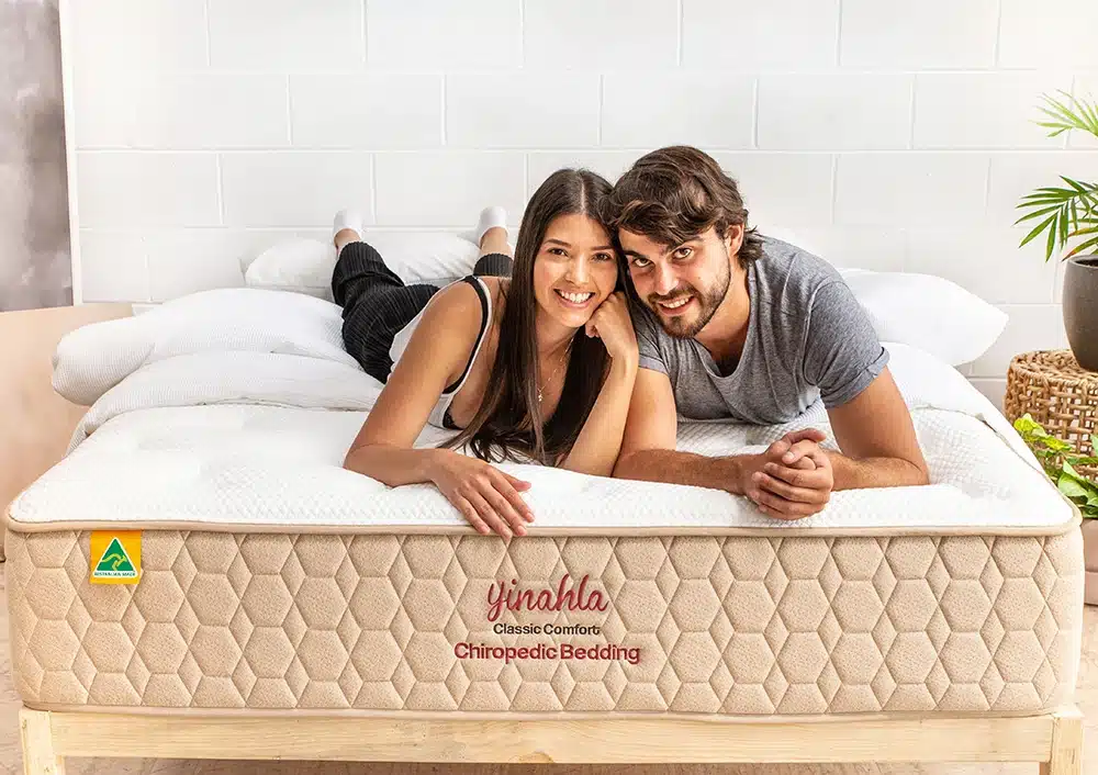 Smiling Couple sitting on Classic Comfort Mattress